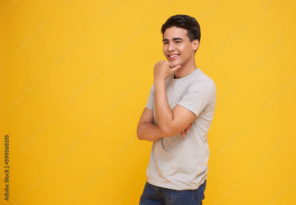 Smart handsome smiling young Asian man thinking with hand on chin isolated on yellow studio background Smart handsome smiling young Asian man thinking with hand on chin isolated on yellow studio background