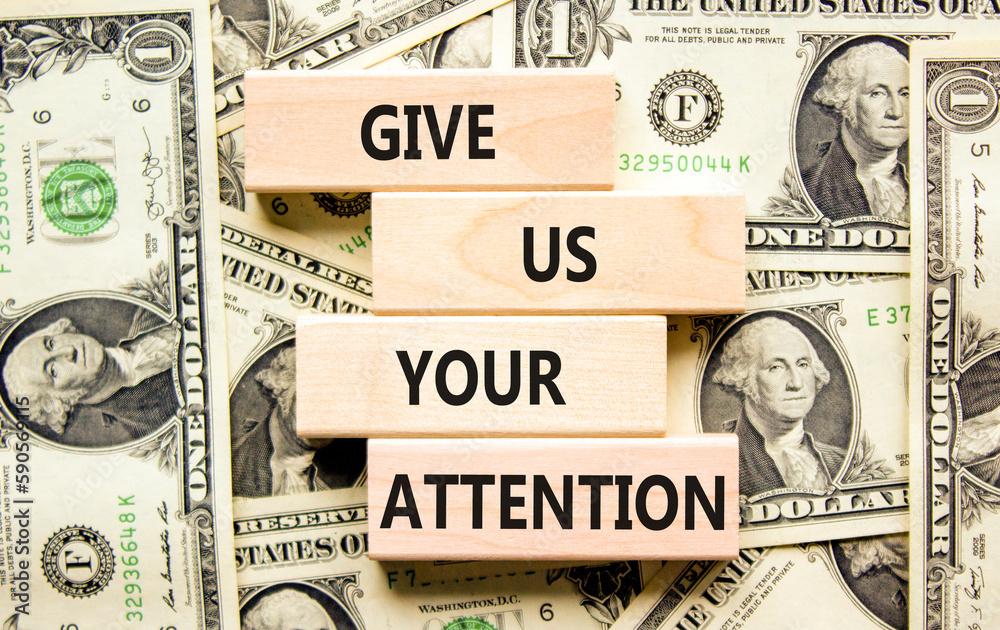 Give us your attention symbol. Concept words Give us your attention on wooden block. Beautiful background from dollar bills. Motivational business give us your attention concept. Copy space.