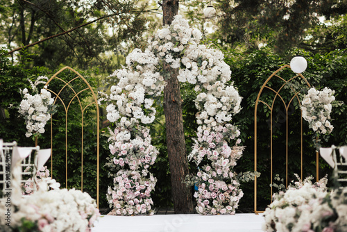 Outgoing wedding ceremony in the forest. White chairs and wedding arch at nature. Wedding festal arch. 
