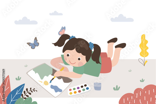 Cute little girl lies on the grass and draws landscape with paints. Happy child in nature having fun. Little caucasian girl artist paints with watercolors. Education, art
