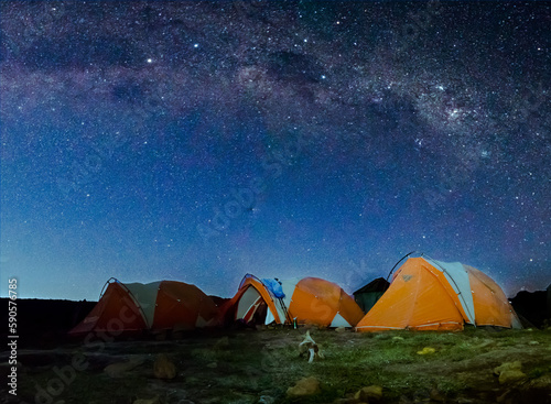 Orange tents illuminated before Mount Kilimanjaro and bright Milky Way