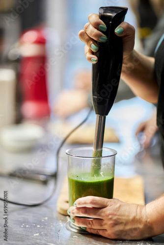 the cook prepares a vegetable puree with a hand blender, close-up. Preparation of broccoli cream soup with an immersion blender.