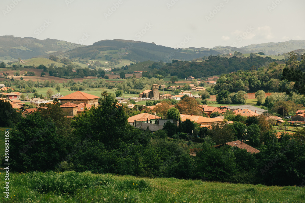 A view of a European village or city in a mountainous area. Buildings and housing in the foreground, and mountains in the background