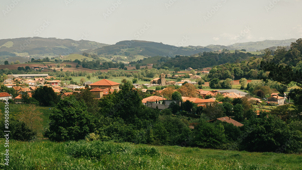 A view of a European village or city in a mountainous area. Buildings and housing in the foreground, and mountains in the background