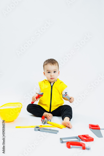A 2-year-old boy plays with plastic construction tools. Children's plastic toys. Children's builder's set.