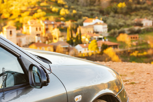 Small green grey car, automobile standing on top of a hill, an observation deck overlooking the rooftops of an old European city. Spanish holidays travel in summer day rip on a car. Postcard vacations