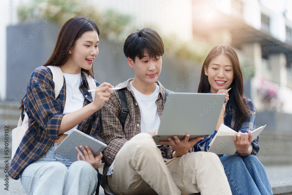 Fototapeta premium Young Asian woman college student with friends at outdoors. College student working on the college campus, education, school, study