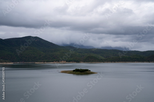 Beautiful view of Dam Cabra Corral placid lake and green hills in a cloudy day. 