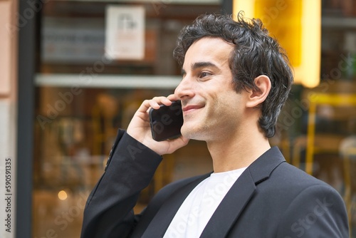 Young businessman multitasking with a phone call while enjoying a drink at a stylish bar.