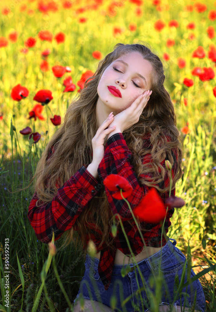 Young blonde woman in cowboy style outfit in poppy field sitting on ground. Girl with red lips and closed eyes Young blonde woman in cowboy style outfit in poppy field sitting on ground. Girl with red lips and closed eyes