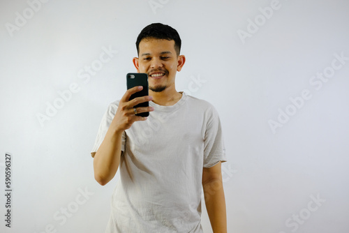 Adult Asian man holding mobile phone showing enthusiastic expression photo