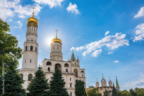 Ivan the Great Bell Tower, with Assumption Belfry on the right in Moscow Kremlin. Blue sky background with sunbeams photo