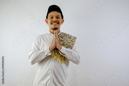 Handsome Moslem Asian man smiling while doing hand praying gesture photo