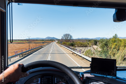 View from the driver's position of a truck of a conventional two-way road between cultivated fields. Country road.