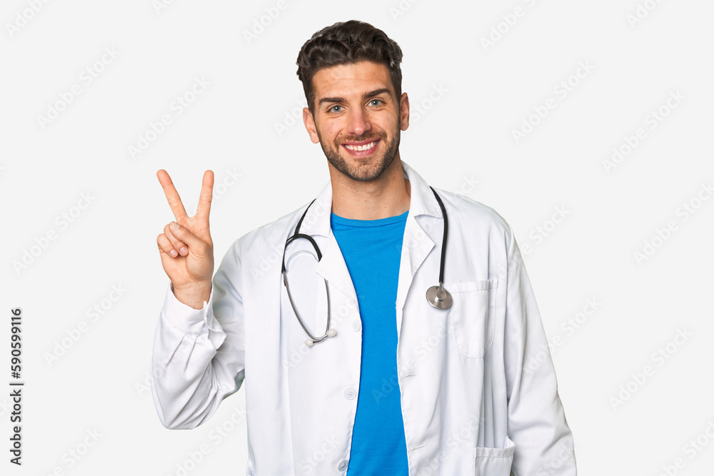 Young doctor man joyful and carefree showing a peace symbol with fingers. Young doctor man joyful and carefree showing a peace symbol with fingers.