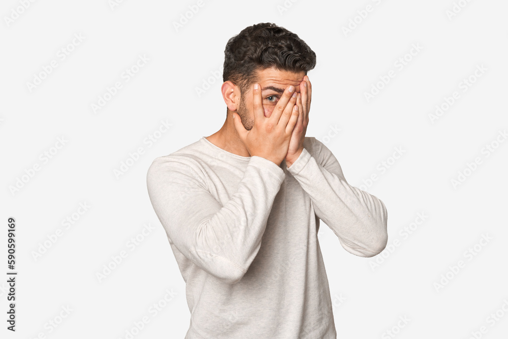 Young handsome man isolated blink through fingers frightened and nervous. Young handsome man isolated blink through fingers frightened and nervous.