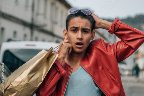 young latin hispanic man with shopping bag and amazing expression in the street © tetxu