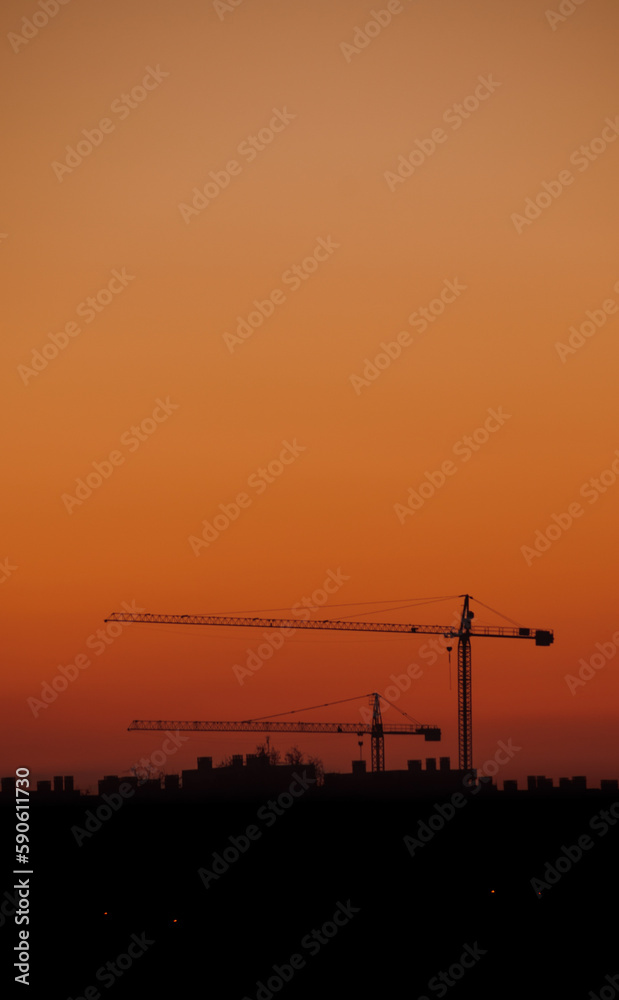 Orange sunset with construction cranes