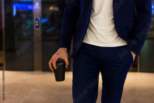 A successful businessman in a dark blue suit with a coffee cup, going through the mall. shop owner.