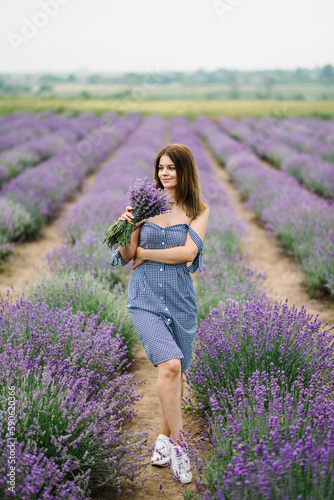 Fototapeta Naklejka Na Ścianę i Meble -  Beautiful girl hold bouquet purple lavender flowers in field. Female collect lavender. Woman in the lavender field. Enjoy the floral glade, summer. Down view. Close up
