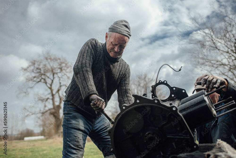 tractor car engine repair at home, old man repairs the engine.