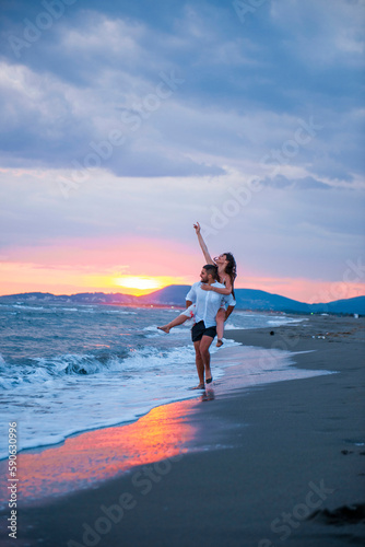 Sunset Romance: Man Carrying Woman on Beach