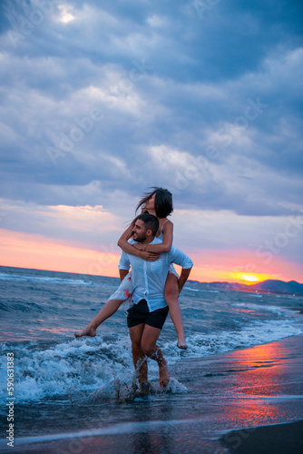 Sunset Romance: Man Carrying Woman on Beach