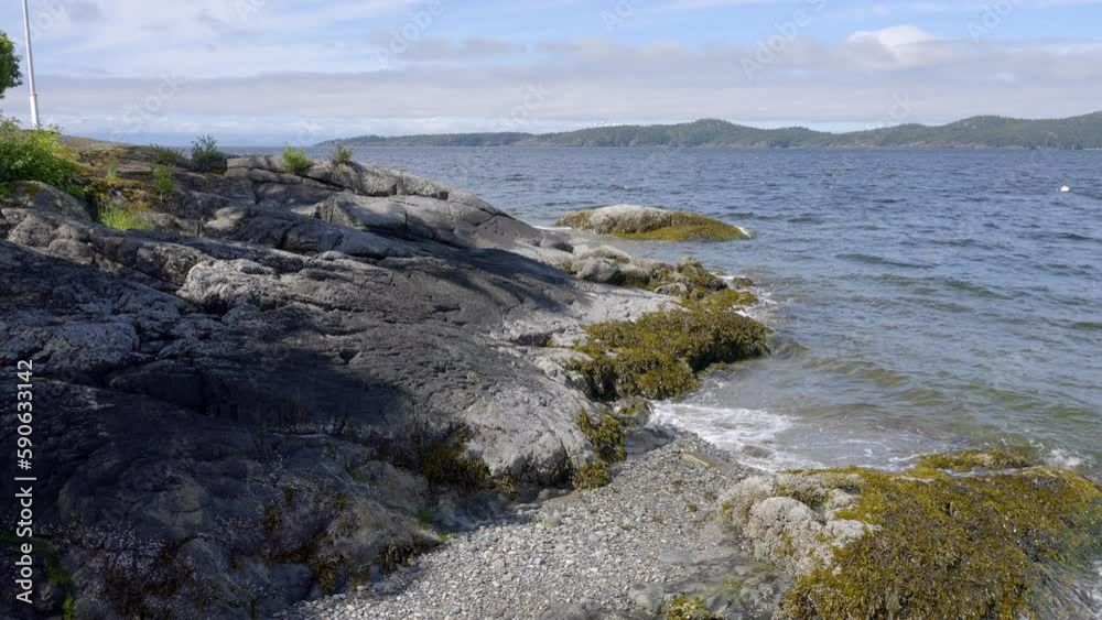 Establishing shot of ocean beach with waves and rocks in slow motion at summer day in Vancouver, Canada, North America. Day time on February 2023. Still camera. ProRes 422 HQ. Establishing shot of ocean beach with waves and rocks in slow motion at summer day in Vancouver, Canada, North America. Day time on February 2023. Still camera. ProRes 422 HQ.