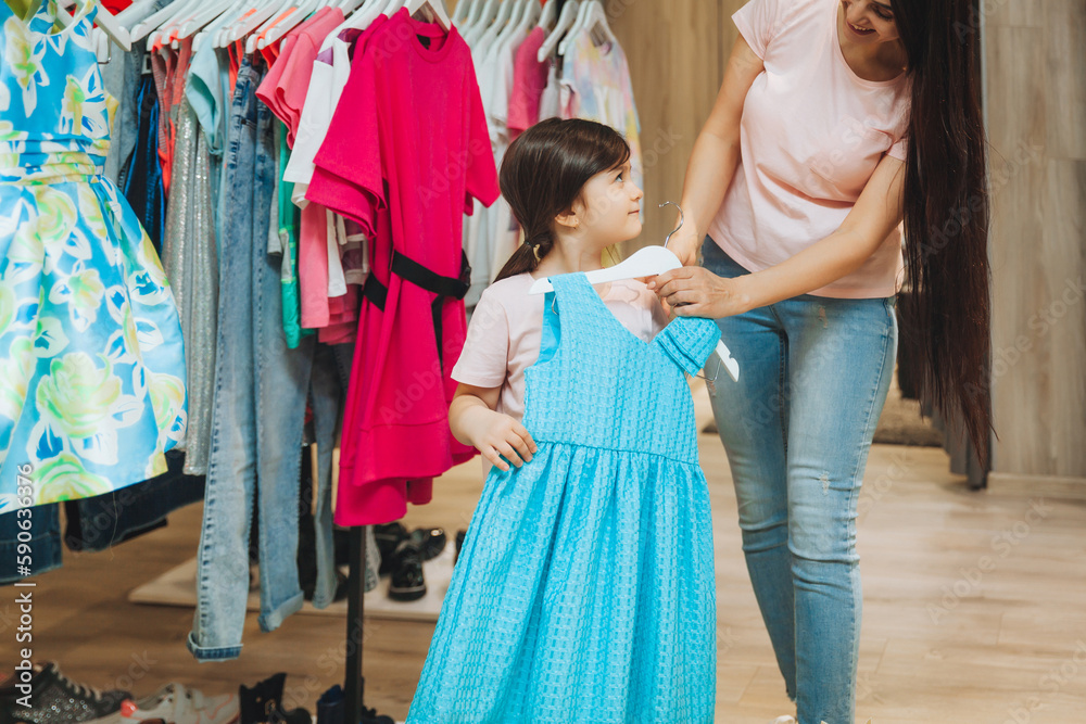 mother and daughter buy clothes. mother and little girl trying on clothes in the shop