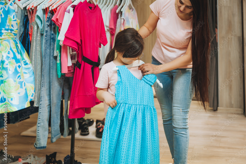 mother and daughter buy clothes. mother and little girl trying on clothes in the shop