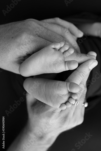 Black and white shade beautiful shape hands of mother, hold tiny newborn baby feet on black background with love, care, family safety and protection, child with premature birth concept or NICU care © Vad-Len