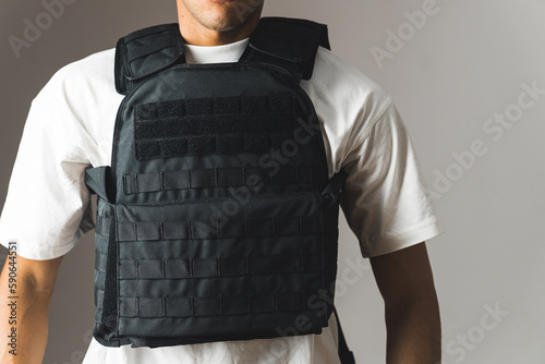 a muscular unknown man in a white T-shirt wearing a bulletproof vest on a grey background. High quality photo photo