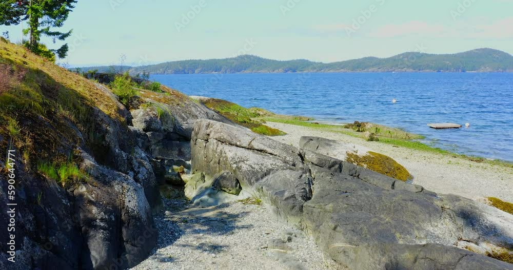 Establishing shot of ocean beach with waves and rocks in slow motion at summer day in Vancouver, Canada, North America. Day time on February 2023. Still camera. ProRes 422 HQ. Establishing shot of ocean beach with waves and rocks in slow motion at summer day in Vancouver, Canada, North America. Day time on February 2023. Still camera. ProRes 422 HQ.