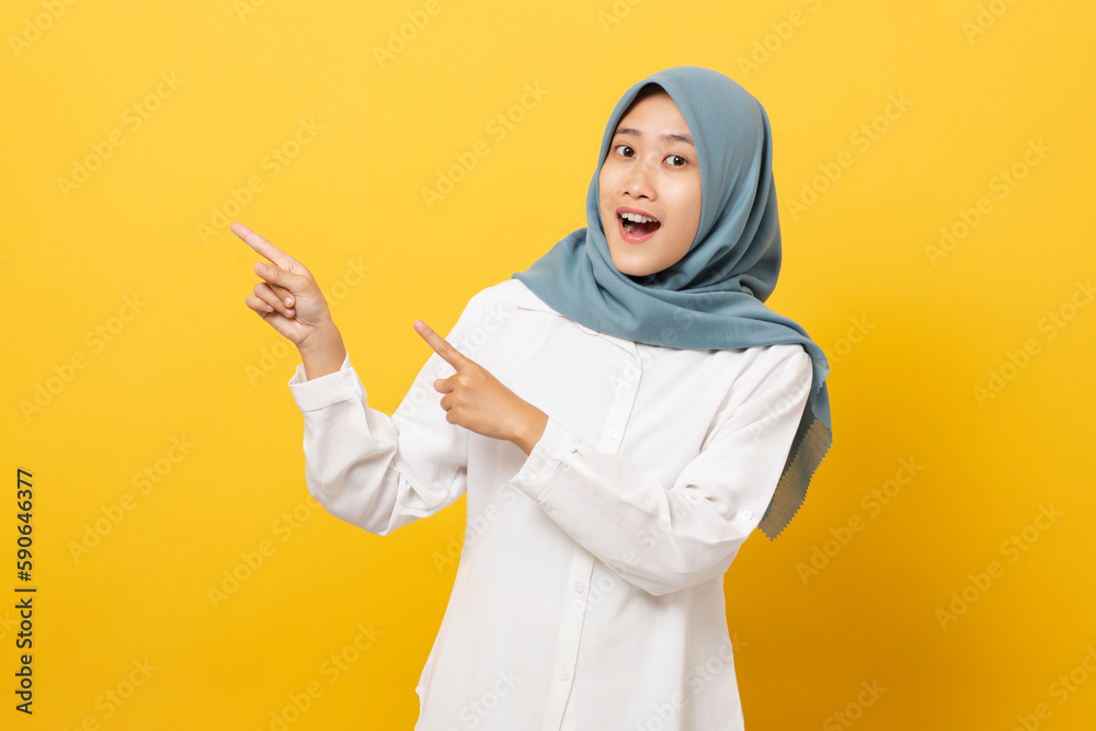 Young asian muslim woman pointing finger into blank space isolated over orange background. marketing advertising presenting product. Young asian muslim woman pointing finger into blank space isolated over orange background. marketing advertising presenting product.