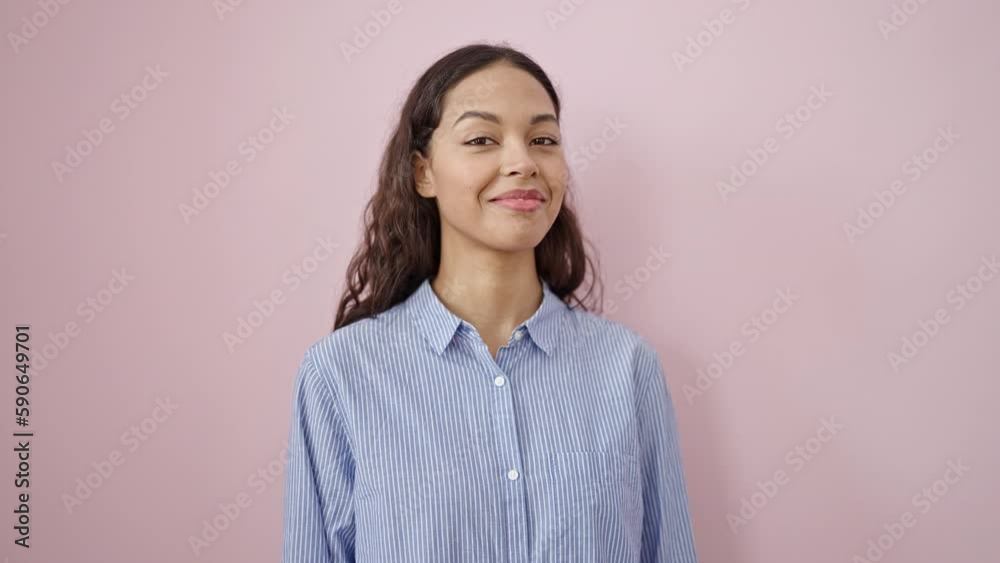 Young beautiful hispanic woman smiling confident saying yes with head over isolated pink background
