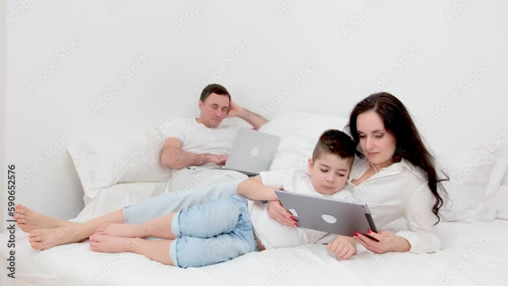 freelance work allows family to be together father works on computer laptop in bed at home mom and son play on tablet have great time with family woman and boy have fun relaxing man earn money freelance work allows family to be together father works on computer laptop in bed at home mom and son play on tablet have great time with family woman and boy have fun relaxing man earn money