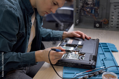 Professional engineer restores the laptop PC using various special tools. Electronic repair shop, technology renovation, business, concept repairs. man repairing parts of disassembled laptop