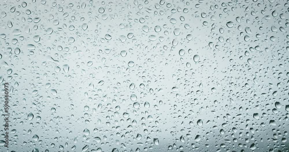 Close-up of water droplets on glass. Rain drops on window pane during a summer shower. Close-up of water droplets on glass. Rain drops on window pane during a summer shower.