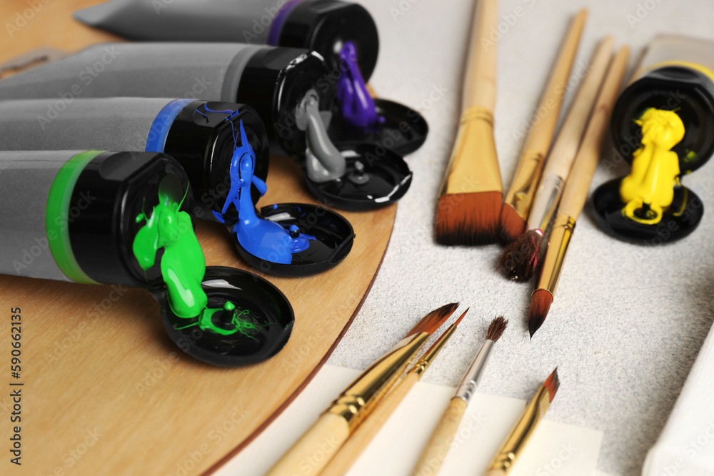 Tubes of colorful paints and brushes on textured table, closeup Tubes of colorful paints and brushes on textured table, closeup