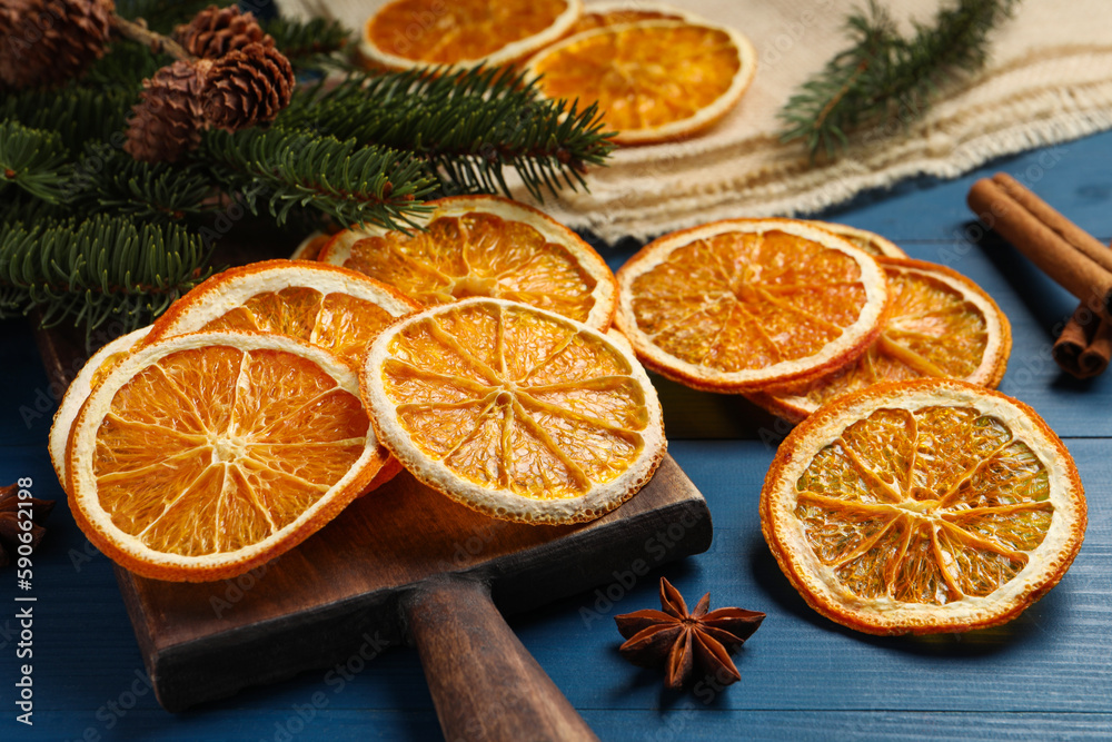 Dry orange slices, cinnamon and anise stars on blue wooden table, closeup