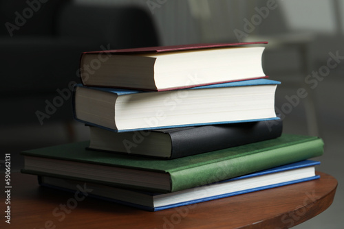 Stack of hardcover books on wooden coffee table indoors, closeup