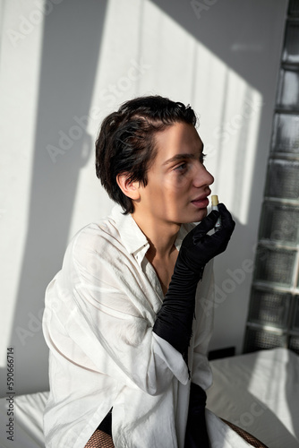 young actor using lipbalm before performance, close up side view portrait. beauty conmcept, skin face care photo