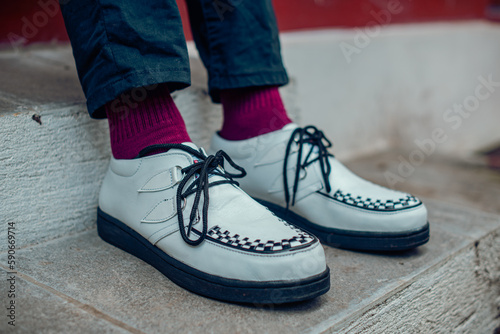 Close up of these white creepers sneakers made of genuine leather with black soles that men wear to sit on. These casual yet elegant shoes are handmade by home shoe craftsmen