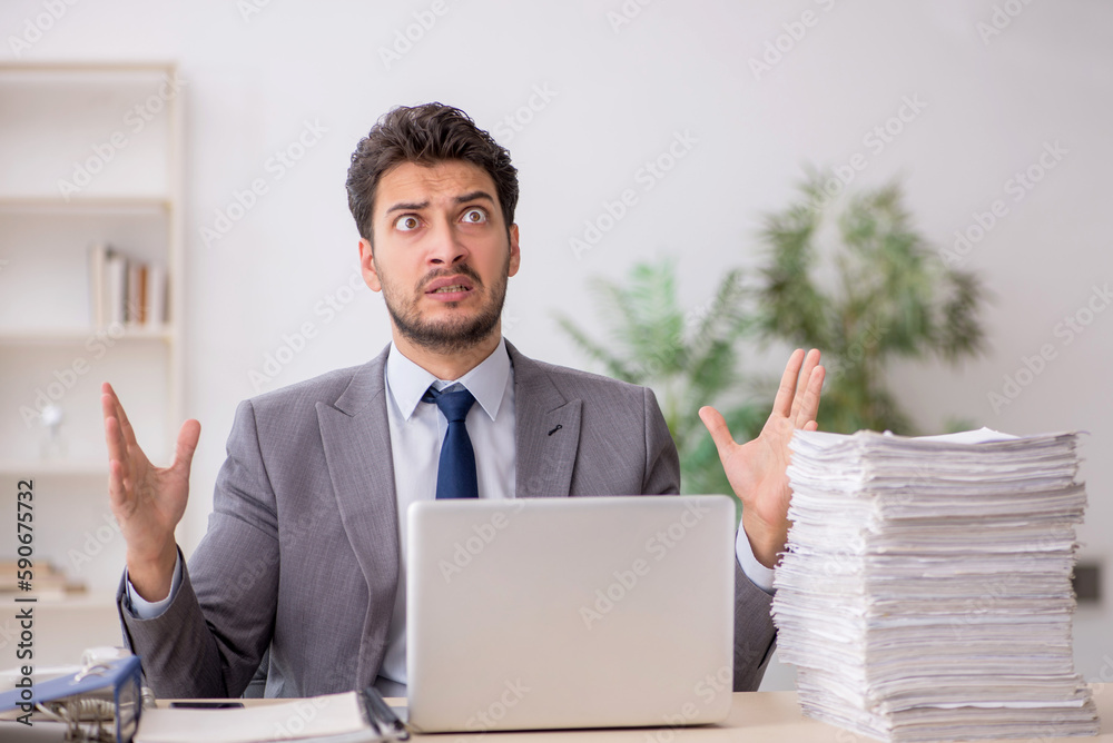Young male employee and too much work in the office Young male employee and too much work in the office
