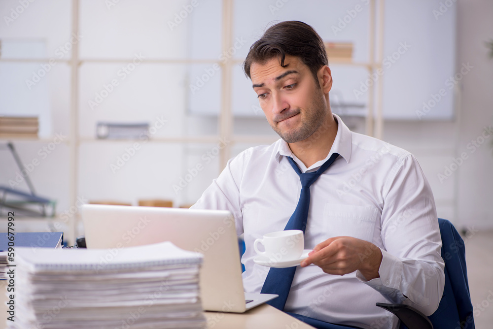 Young male employee and too much work in the office Young male employee and too much work in the office