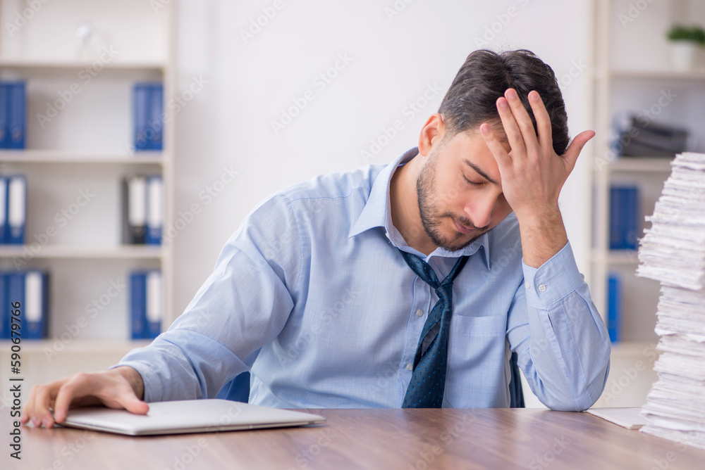 Young male employee and too much work in the office Young male employee and too much work in the office