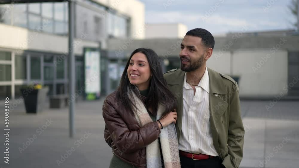 A Middle Eastern couple strolling together on the sidewalk of an urban street. Tracking shot in motion of a joyful man and woman walking forward A Middle Eastern couple strolling together on the sidewalk of an urban street. Tracking shot in motion of a joyful man and woman walking forward
