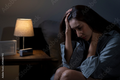 Young Asian woman in bedroom feeling sad tired and worried suffering depression in mental health, woman sitting in bed cannot sleep from insomnia.