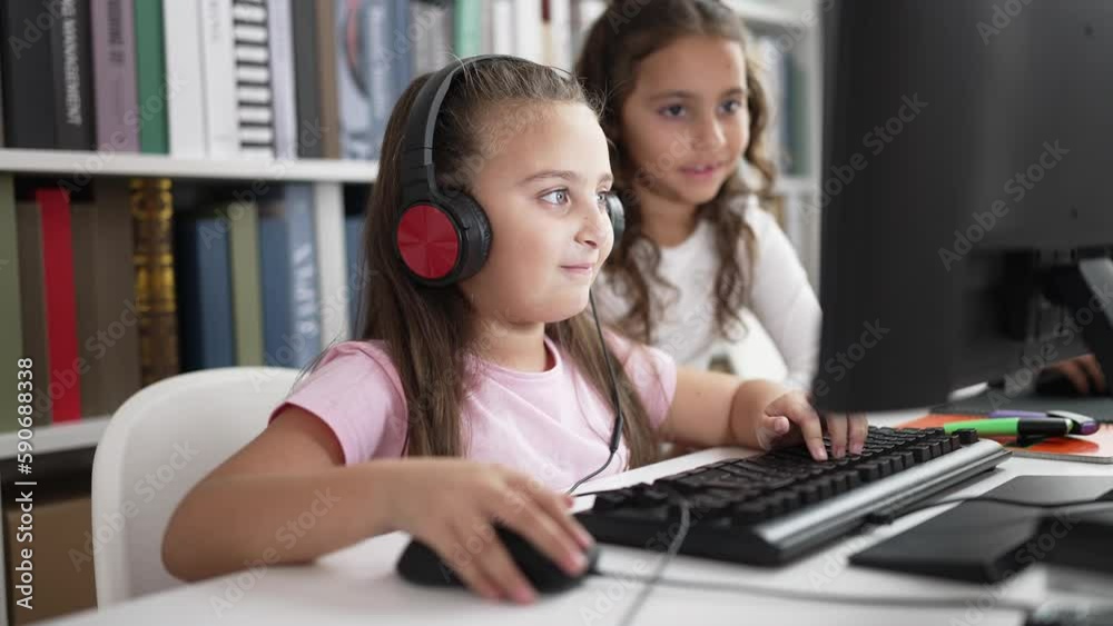 Adorable girls students using computer and headphones studying at classroom Adorable girls students using computer and headphones studying at classroom