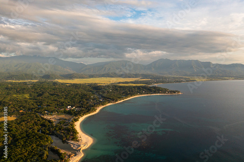 Aerial drone of coastline with a beach during sunset against the backdrop of mountains. Pagudpud  Ilocos Norte  Philippines.